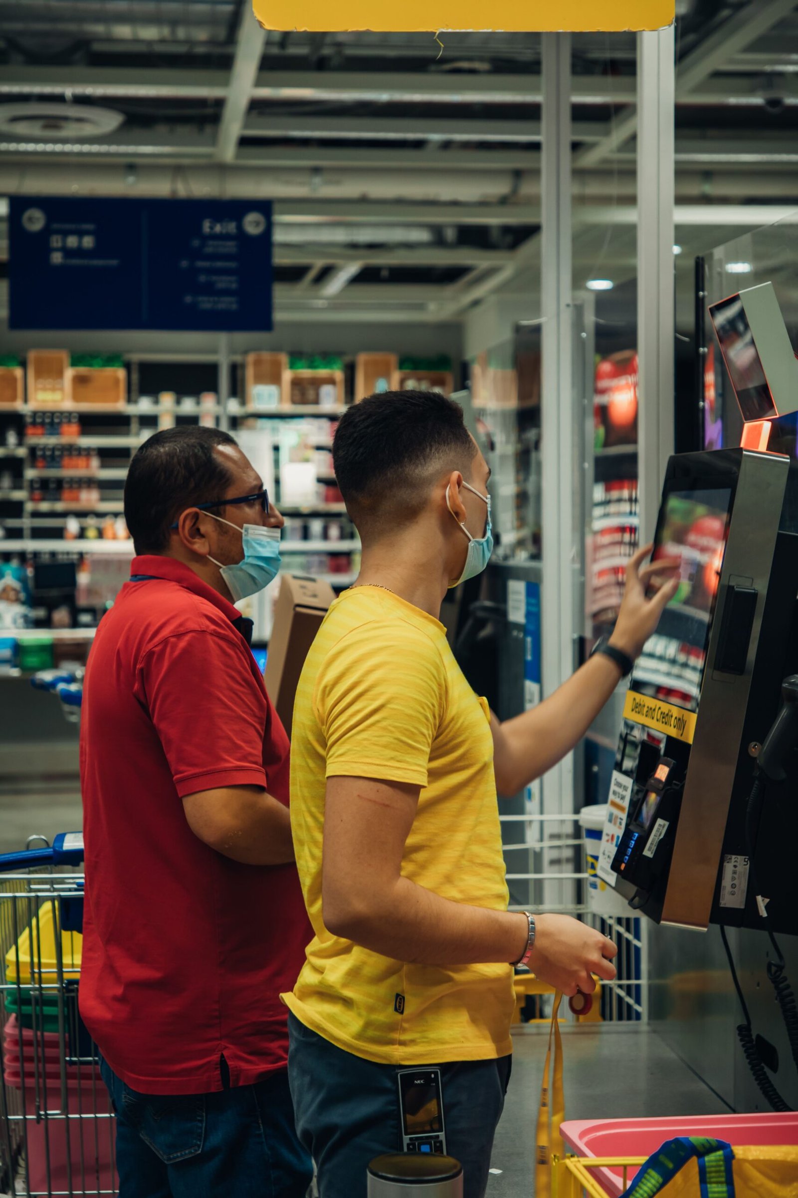 Customer asking for help at a grocery self-checkout station while items are being scanned